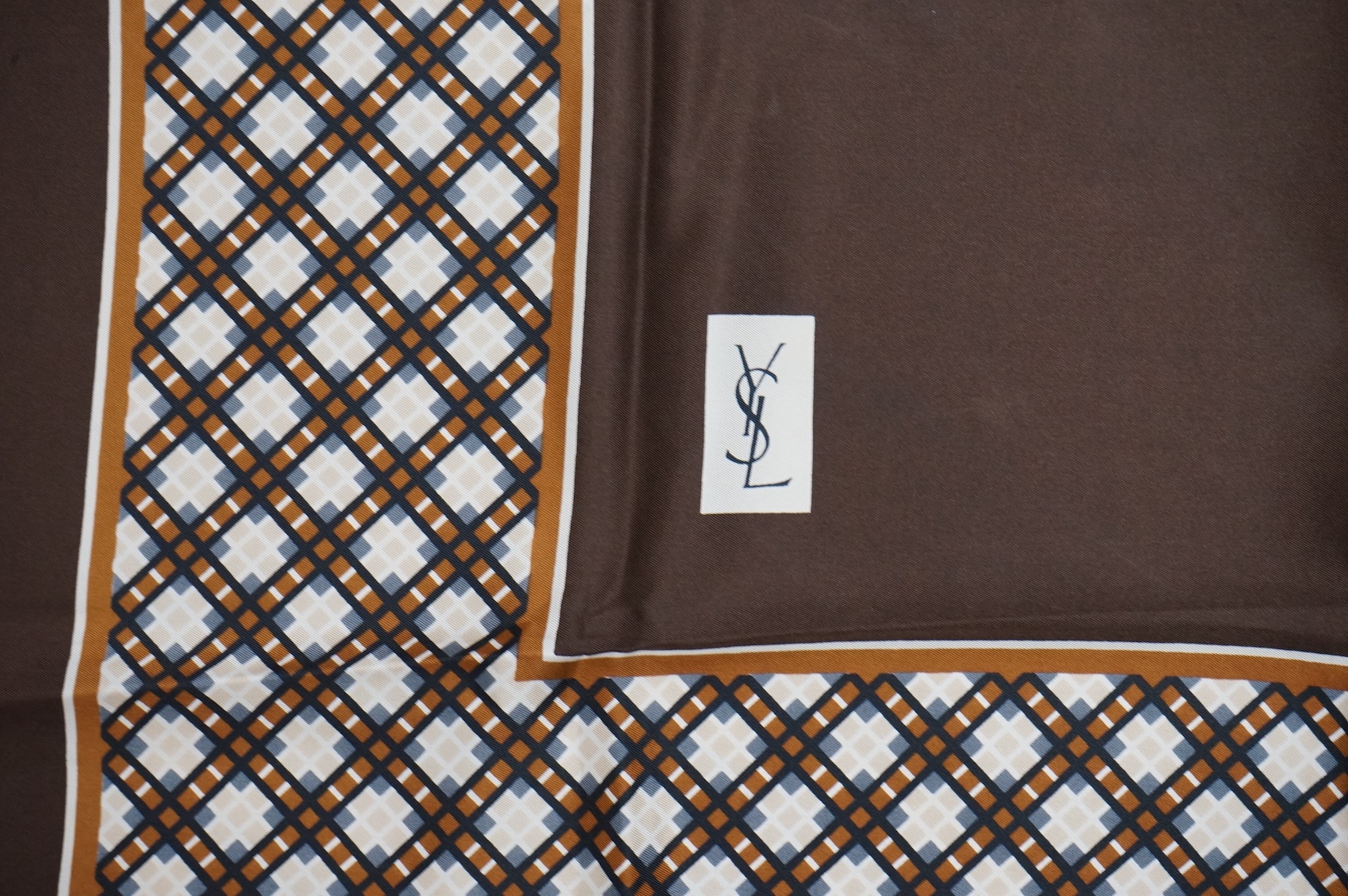 Two Yves Saint Laurent silk scarves comprising a monogrammed example and a patterned brown example with Foulards folding case
